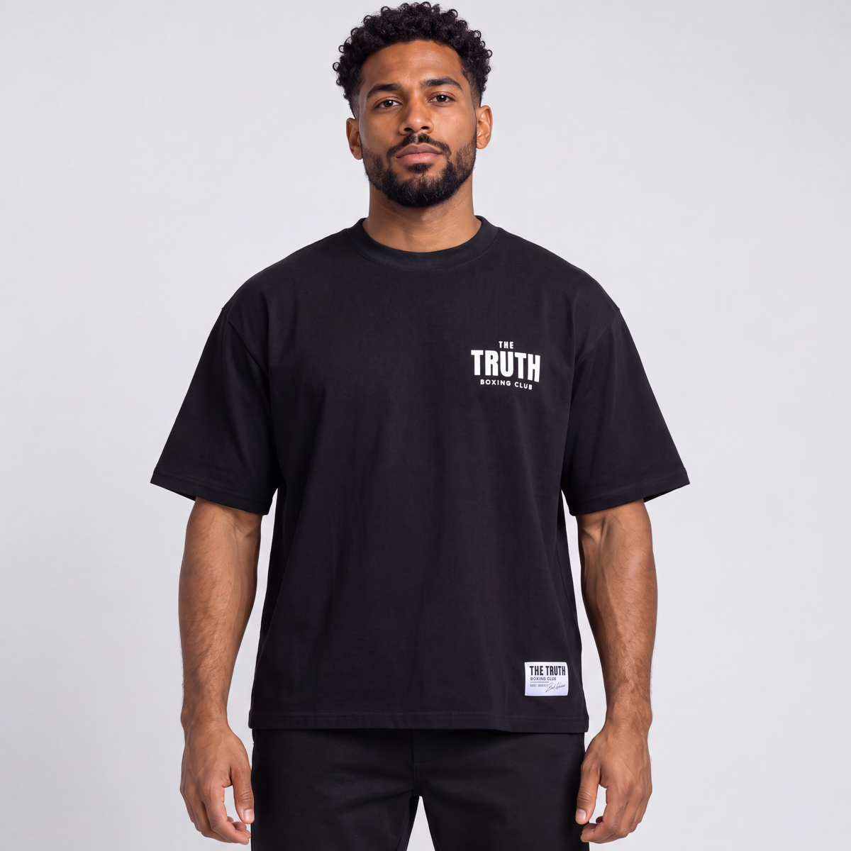 Front view of The Truth Boxing Club black tee with white chest logo and hem label.